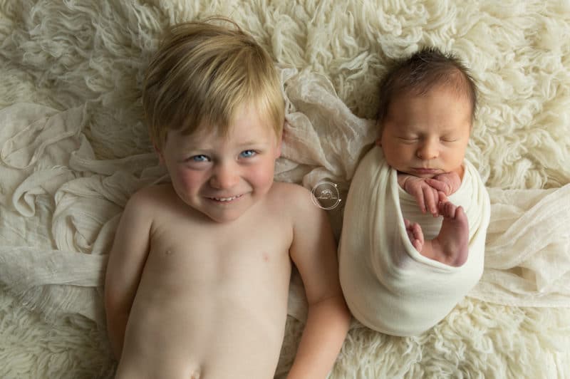 Un bébé et son grand frère pendant une séance photo