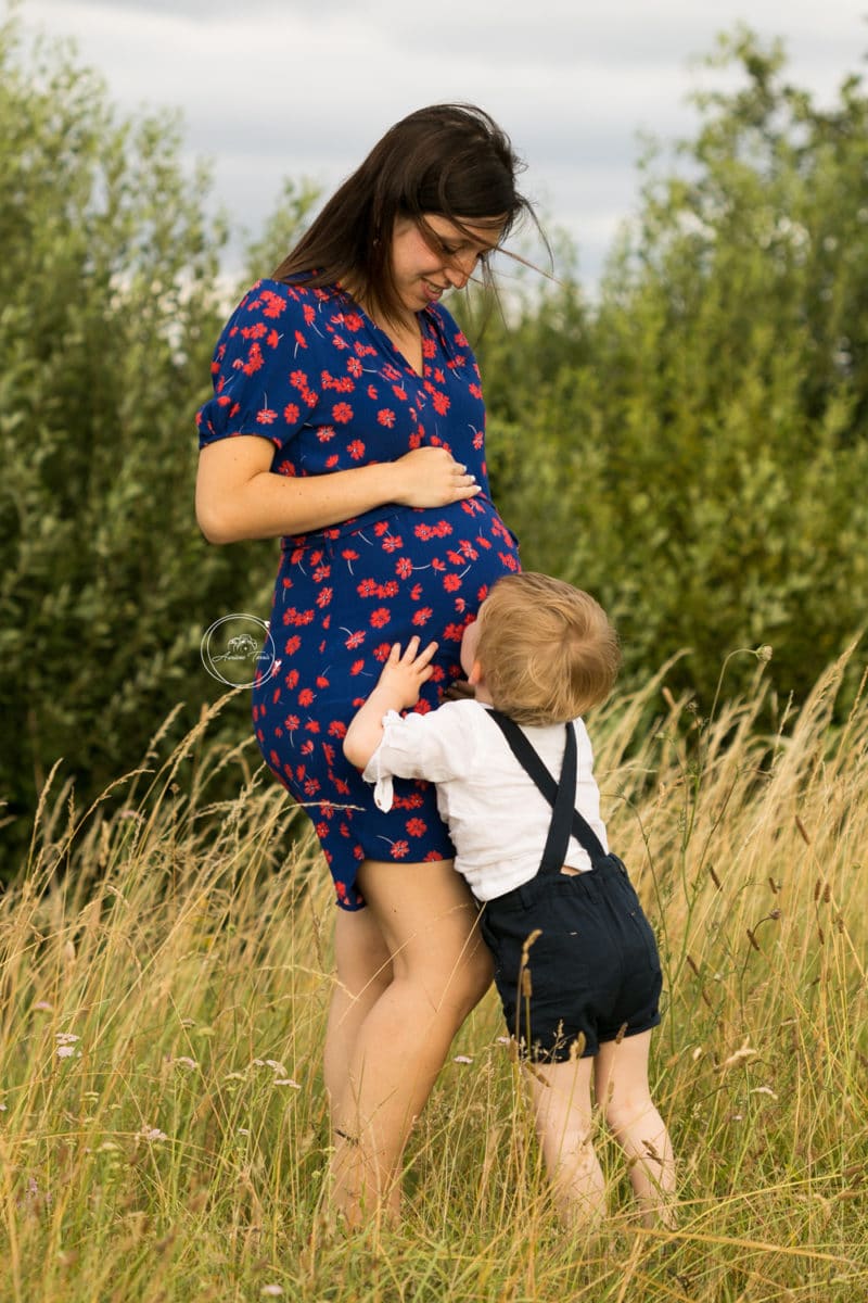 Photo d'un enfant qui fait un bisou sur le ventre de sa maman enceinte