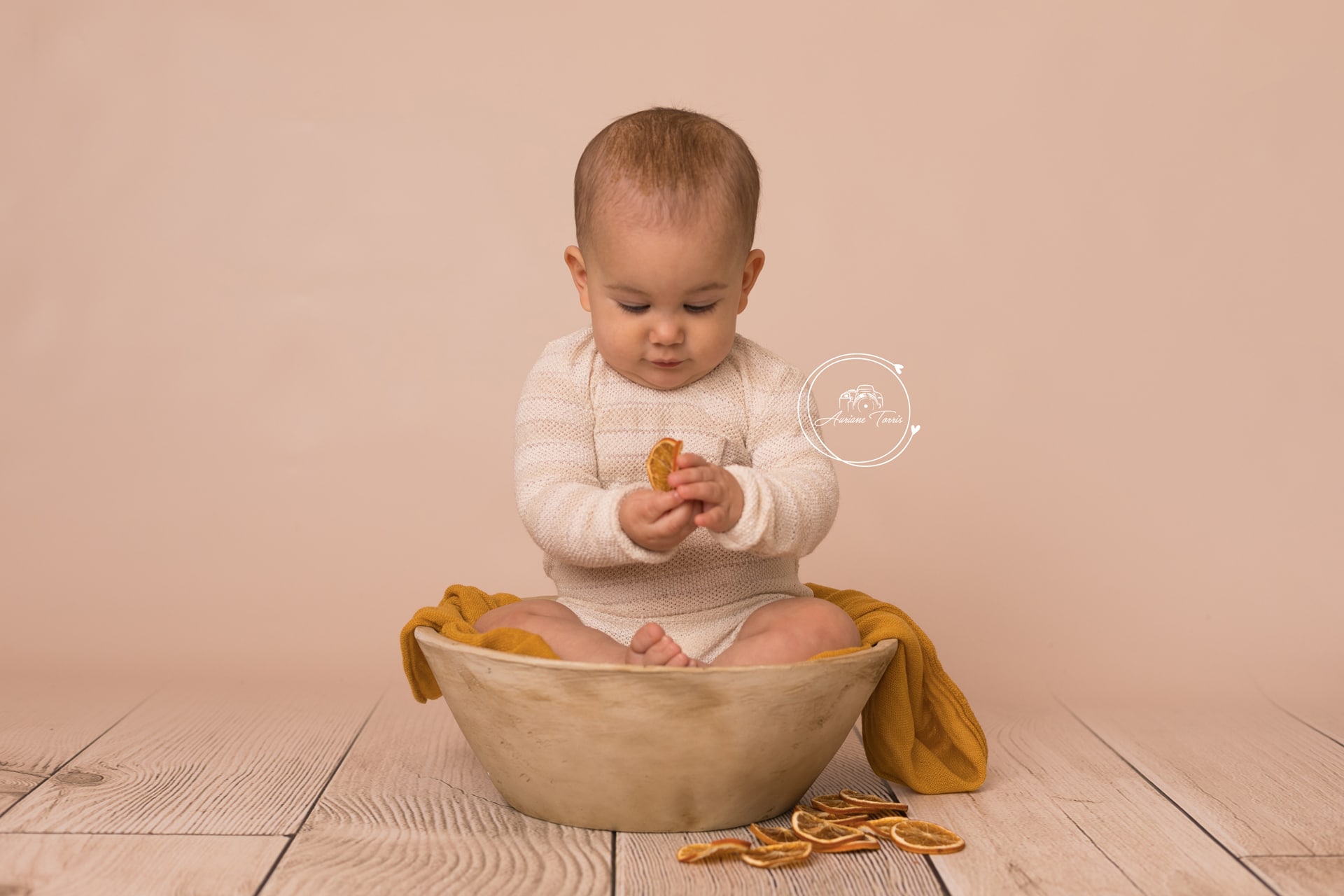 Photo d'un bébé dans un décor moutarde avec des rondelles d'orange